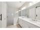 Modern bathroom features double sinks, white cabinets, and a large shower with glass door and gray tile at 9970 Cross River Trl, Parrish, FL 34219
