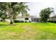 Spacious backyard with lush green lawn, mature trees, and a screened lanai at 1311 Tuscany Blvd, Venice, FL 34292