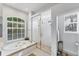 Bright bathroom featuring soaking tub, glass enclosed shower, and large window at 1311 Tuscany Blvd, Venice, FL 34292