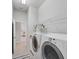 Bright laundry room with appliances, shelving, and neutral tile flooring leading to other rooms at 1311 Tuscany Blvd, Venice, FL 34292