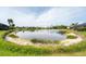 Scenic view of a tranquil pond surrounded by green grass and landscaping at 1311 Tuscany Blvd, Venice, FL 34292