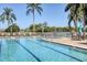 Community pool featuring lane markers, shallow area, lounge chairs, and palm trees at 1311 Tuscany Blvd, Venice, FL 34292