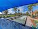 Bocce ball court with seating, lush landscaping, palm trees, and blue awning overhead at 13167 Fernando St, Venice, FL 34293