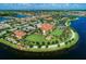 Aerial view of a beautifully landscaped clubhouse, lush green lawn, and palm trees near the lake at 13167 Fernando St, Venice, FL 34293