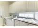 Bright laundry room with white cabinets, sink, and modern washer and dryer appliances at 13167 Fernando St, Venice, FL 34293