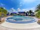 Gathering-friendly swimming pool with water fountains, blue umbrellas, lounge chairs, palm trees, and blue skies at 13167 Fernando St, Venice, FL 34293