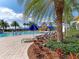 Inviting swimming pool area with palm trees, colorful landscaping, blue umbrellas, and comfortable lounge chairs at 13167 Fernando St, Venice, FL 34293