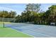 Full tennis court, fenced, with green and blue surface, surrounded by trees and a bench at 1624 Stickney Point Rd # 204, Sarasota, FL 34231