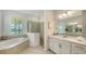 Bright bathroom featuring dual vanities, a garden tub, and glass shower at 17449 Sandpearl Rd, Venice, FL 34293