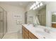 Bright bathroom featuring double sinks, a large mirror, and walk-in shower with tiled walls at 19038 Lappacio St, Venice, FL 34293