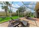 The screened in lanai includes brick patio, table, chairs, umbrella and lounge chairs at 19038 Lappacio St, Venice, FL 34293