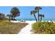 Scenic beach view with palm trees, colorful umbrellas, and lounge chairs for ultimate relaxation at 20 Whispering Sands Dr # 1201, Sarasota, FL 34242