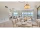 Open-concept dining area and living room with ocean views, chandelier, and contemporary decor at 20 Whispering Sands Dr # 1201, Sarasota, FL 34242