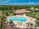 Aerial view of a resort-style pool with lounge chairs and tables, alongside a playground and beautifully landscaped surroundings at 224 Dahlia Ct, Bradenton, FL 34212