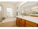 Bright bathroom featuring double sinks, glass enclosed shower, and soaking tub by an arched window at 224 Dahlia Ct, Bradenton, FL 34212