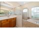 Bright bathroom featuring double sinks, glass enclosed shower, and soaking tub by an arched window at 224 Dahlia Ct, Bradenton, FL 34212