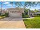 Neutral colored single-story home, featuring a 2-car garage, well manicured shrubbery, and lush green lawn at 224 Dahlia Ct, Bradenton, FL 34212