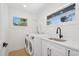 Bright laundry room with modern washer and dryer, white cabinetry, quartz counters, and a stylish black faucet at 2655 Bay St, Sarasota, FL 34237