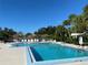 Community pool with lounge chairs and tiki umbrellas, surrounded by palm trees and a tennis court at 3002 Sail Pointe Cir # 1B, Venice, FL 34293