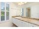 Bathroom vanity with marble countertop, framed mirror, white cabinets, and window with shutters at 4625 Deer Creek Blvd, Sarasota, FL 34238