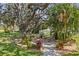 Charming backyard patio with seating surrounded by mature trees and manicured landscaping, creating a tranquil outdoor setting at 4712 Charles Partin Dr, Parrish, FL 34219