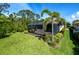 Well-maintained backyard featuring a screened lanai, lush lawn, and mature landscaping for privacy at 5301 Bartolomeo St, Sarasota, FL 34238