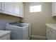 Well-lit laundry room features modern washer and dryer with white cabinets at 5301 Bartolomeo St, Sarasota, FL 34238