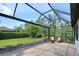 Inviting screened patio with stone floors, lounge chairs, and green space beyond at 5301 Bartolomeo St, Sarasota, FL 34238