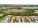 An aerial view shows a residential neighborhood with lush green trees, sidewalks, and a pond nearby at 620 Nasturtium Ct, Nokomis, FL 34275