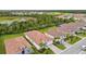 An aerial view shows a residential neighborhood with houses that have red tile roofs, lush green trees, and a pond nearby at 620 Nasturtium Ct, Nokomis, FL 34275