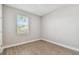 An empty bedroom with wood-look tile floors, neutral walls, one window, and white trim creating a bright, serene space at 620 Nasturtium Ct, Nokomis, FL 34275