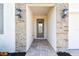Inviting entryway with stone-accented columns, decorative lighting, and a brick-paved walkway at 620 Nasturtium Ct, Nokomis, FL 34275