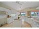 Bright kitchen featuring white cabinets, an island, granite countertops, tile flooring, and views of the lake at 6408 Rookery Cir, Bradenton, FL 34203