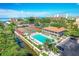 Aerial view of resort-style amenities including a pool, tennis courts, and waterfront access with buildings nearby at 6415 Midnight Pass Rd # 710, Sarasota, FL 34242