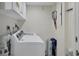 Laundry room with white washer and dryer, overhead cabinet, and tennis racket at 6415 Midnight Pass Rd # 710, Sarasota, FL 34242