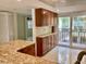 Kitchen features wood cabinets, granite countertops, tile flooring, and sliding glass doors to the balcony at 6430 Sun Eagle Ln # 203, Bradenton, FL 34210