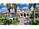 Elegant two-story home featuring a red tile roof, arched entrance, and lush tropical landscaping at 8016 Bounty Ln, Bradenton, FL 34202
