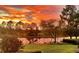Picturesque sunset reflecting off the tranquil pond with lush landscaping at 8016 Bounty Ln, Bradenton, FL 34202