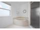Bright bathroom featuring a soaking tub, glass enclosed shower and a window at 802 N Bay Blvd, Anna Maria, FL 34216