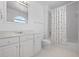 Bright white bathroom with a tub-shower combination, shell-patterned curtain, and ample cabinet space at 802 N Bay Blvd, Anna Maria, FL 34216