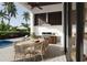 Outdoor kitchen and dining area featuring a built-in grill, dining table, and access to pool at 838 Norsota Way, Sarasota, FL 34242
