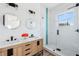 Modern bathroom featuring double vanity, round mirrors, and glass shower at 8622 Inwood Dr, Hudson, FL 34667