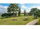 Outdoor lawn area with cornhole game and Adirondack chairs on a sunny day with golf course in the background at 12619 Sorrento Way, Bradenton, FL 34211