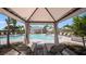 Relax in the cabana overlooking the pool area with lounge chairs and palm trees at 15172 Cuzcorro Ct, Nokomis, FL 34275
