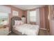 Cozy bedroom with pink accents, a comfortable bed, dresser, and plenty of natural light from the window at 15200 Cuzcorro Ct, Nokomis, FL 34275