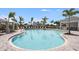 Large community pool with beautiful blue water, surrounded by palm trees and lounge chairs at 15200 Cuzcorro Ct, Nokomis, FL 34275