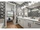 Tastefully decorated bathroom with double sinks, designer wallpaper, and a doorway leading to the main bedroom at 16226 Hidden Oak Loop, Lakewood Ranch, FL 34211