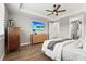 Tranquil main bedroom with a ceiling fan, warm wood flooring, and a glimpse into the ensuite bathroom at 16226 Hidden Oak Loop, Lakewood Ranch, FL 34211