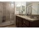 Bathroom with granite counters, cherry cabinets, framed mirror and tiled shower at 17108 Vardon Ter # 401, Bradenton, FL 34211