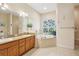 Bathroom featuring double sinks, a soaking tub, and a stained glass window at 18026 Nutcracker Rd, Weeki Wachee, FL 34614